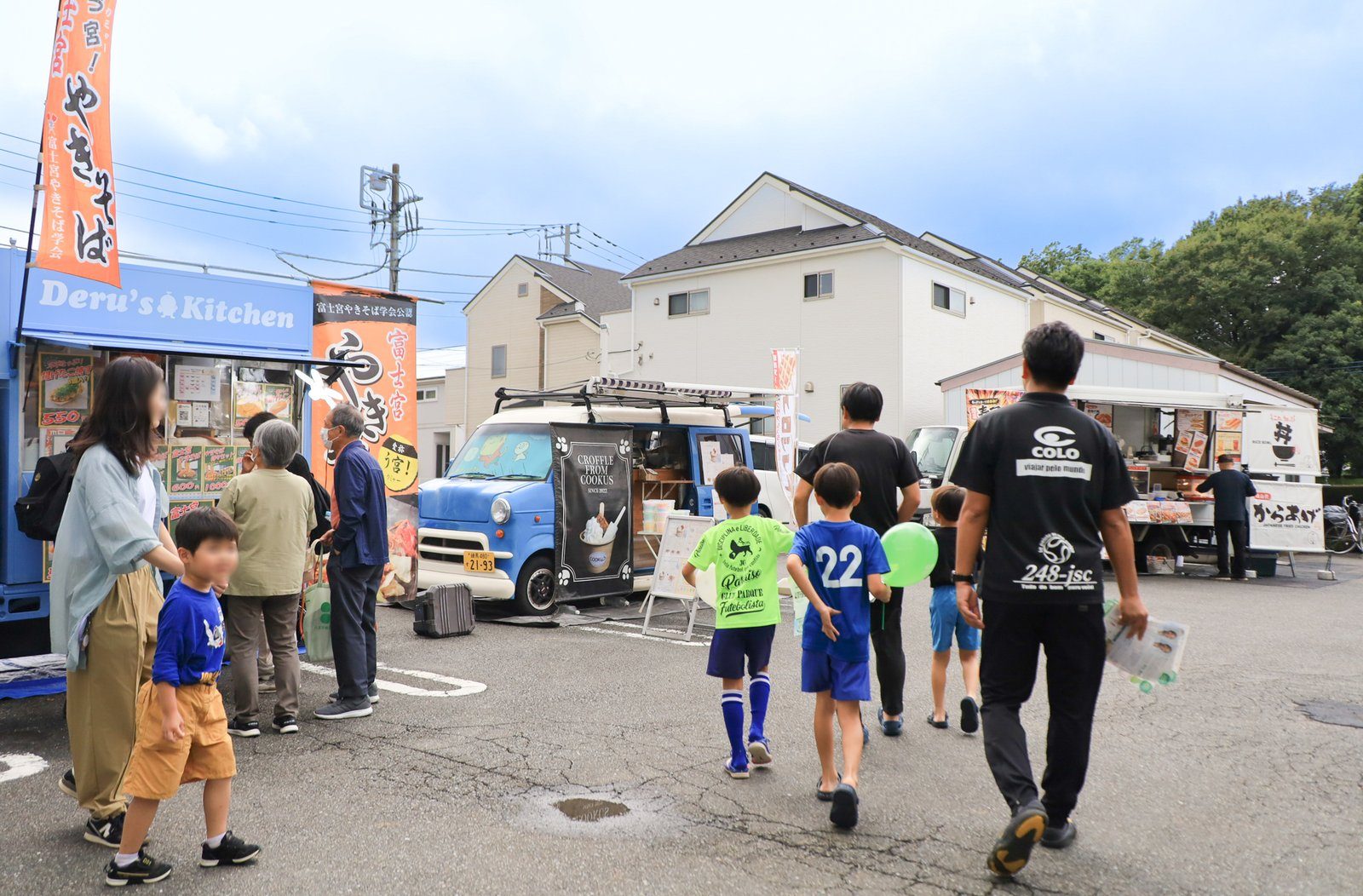 会場の駐車場に並ぶキッチンカーと来場者
